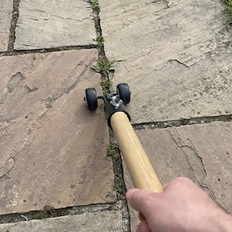 Tuinbezitter die staand onkruid tussen tegels verwijdert