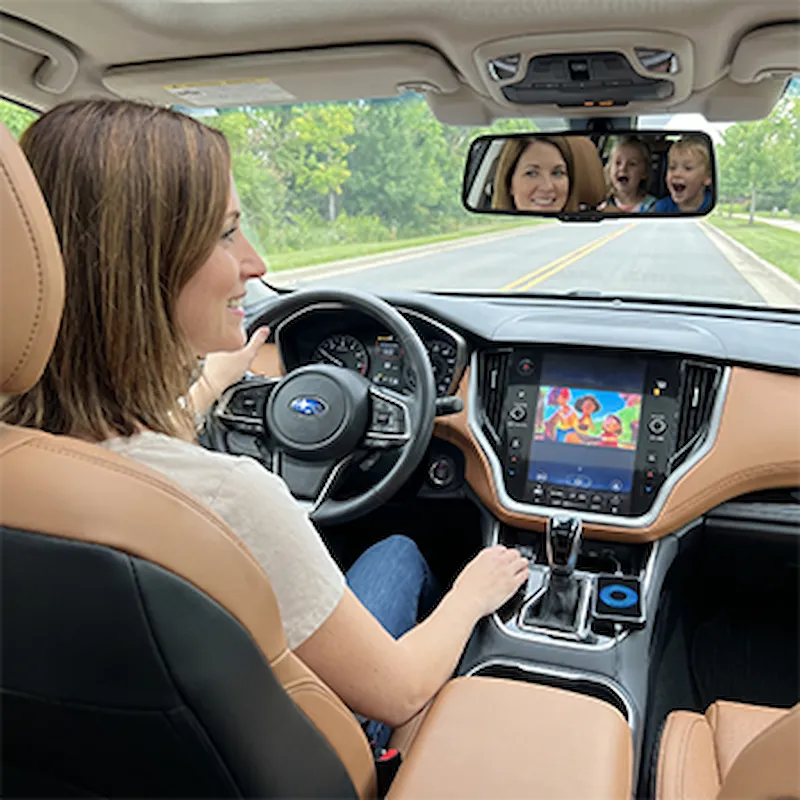 Vrouw rijdt rustig terwijl kinderen op het autoscherm kijken via Roadcast
