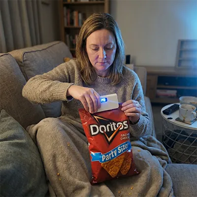 Vrouw die SnapSeal Mini Sealer gebruikt op een chipszak
